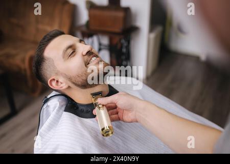 Der Friseur schneidet Haare am Bart eines hübschen Mannes Stockfoto