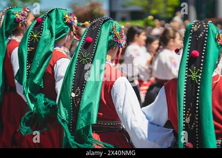 Rückansicht bulgarischer Tänzer in traditionellen nationalen Kostümen, die draußen tanzen, selektiver Fokus Stockfoto