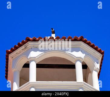 Kapuzenkrähe auf einem Kirchenturm vor blauem Himmel, Griechenland. Stockfoto