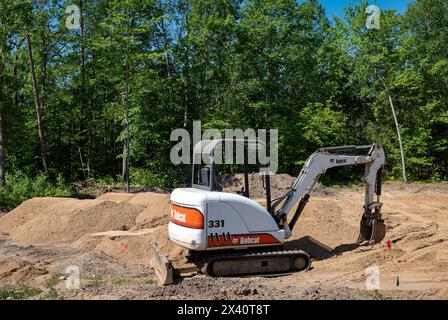 CROW WING CO, MN - 6. JUN 2021: Ein Bobcat 331, Minibagger, mit Kompaktladerketten, sitzt auf einem von Bäumen gesäumten leeren Baugrundstück, in Vorbereitung f Stockfoto