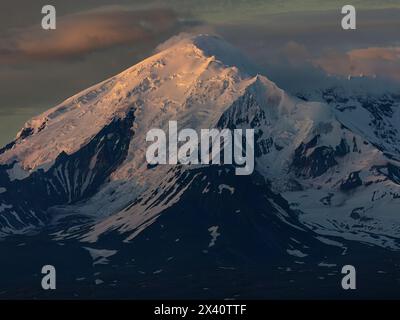 Nahaufnahme des schneebedeckten Mount Drum mit dem alpenglow und Schatten, die seinen Gipfel in Alaskas Wrangell Mountains betonen, spät am Abend in Ohr... Stockfoto