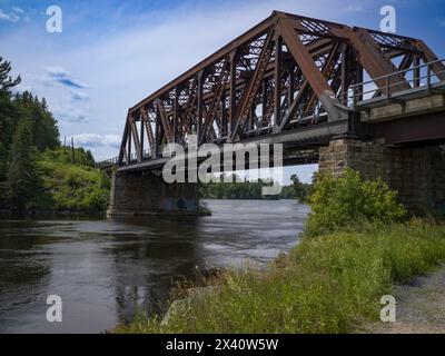 Eisenbahnbrücke über einen Fluss mit einem Wanderweg entlang des Ufers; Lake of the Woods, Ontario, Kanada Stockfoto