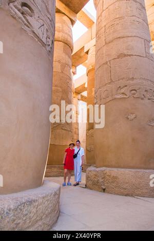 Zwei weibliche Touristen stehen zwischen den riesigen Säulen des Tempelkomplexes Karnak; Luxor, Ägypten Stockfoto