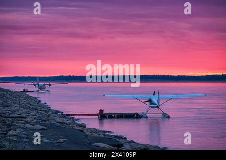 Wasserflugzeuge im Mackenzie River, während die untergehende Sonne die Wolken in wunderschönen Rosa erleuchtet; Fort Simpson, Northwest Territories, Kanada Stockfoto