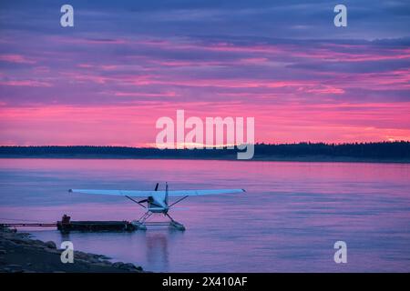 Wasserflugzeug im Mackenzie River, während die untergehende Sonne die Wolken in wunderschönen Rosa erleuchtet; Fort Simpson, Northwest Territories, Kanada Stockfoto