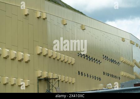 Ein großes Gebäude mit vielen Fenstern und Lüftungsschlitzen. Das Gebäude ist gelb und hat viele Fenster. Stockfoto