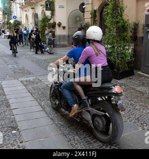 Paare, die mit dem Motorrad durch die Straßen von Alghero, Italien, fahren. Alghero ist eine Stadt an der Nordwestküste Sardiniens. Umgeben von alten... Stockfoto