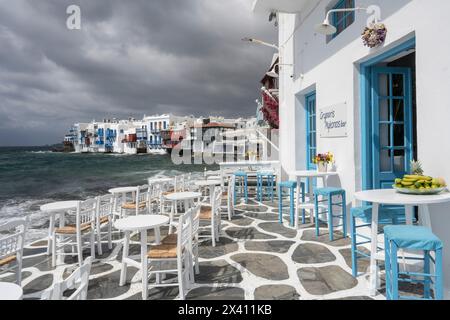 Sitzplätze auf einer Terrasse am Wasser auf der Insel Mykonos mit Blick auf die Fischerhäuser in Little Venice; Mykonos, Griechenland Stockfoto