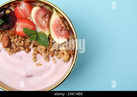 Schüssel mit Joghurt, Obst und Müsli auf hellblauem Hintergrund, Blick von oben. Leerzeichen für Text Stockfoto