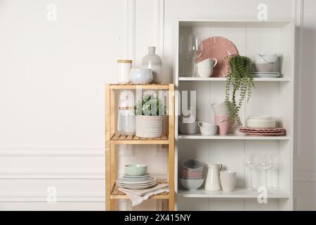 Verschiedene saubere Geschirr und Zimmerpflanzen auf den Regalen im Schrank drinnen Stockfoto