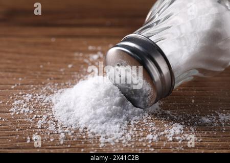 Umgedrehter Shaker mit Salz auf Holztisch, Nahaufnahme Stockfoto