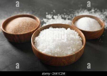 Verschiedene Arten von organischem Salz in Schüsseln auf schwarzem Tisch, Nahaufnahme Stockfoto