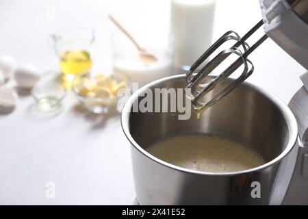 Teig in einer Schüssel des Standmixers auf weißem Tisch zubereiten. Leerzeichen für Text Stockfoto
