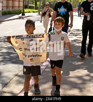 Ein pro-palästinensischer Demonstrant läuft am Sonntag, den 28. April 2024, vor einem von Standrohren abgesperrten Lager auf dem UCLA-Campus. Am Wochenende wurde es gewalttätig, als pro-israelische Aktivisten eine eigene Kundgebung in der Nähe des Lagers veranstalteten. Mary Osako, Vizekanzlerin der UCLA Strategic Communications, gab am Sonntag eine Erklärung heraus, in der es heißt: "Die UCLA hat eine lange Geschichte als Ort des friedlichen Protestes, und wir haben ein gebrochenes Herz zu berichten, dass heute einige physische Auseinandersetzungen unter Demonstranten auf Royce Quad ausbrachen." „Wir haben seitdem zusätzliche Sicherheitsmaßnahmen eingeführt und erhöhen Stockfoto