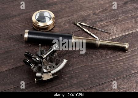 Antike Bronze Marineinstrumente - Sextant, Spionageglas. Marinetrenner und Lupenglas auf altem Holzdeck Hintergrund Stockfoto