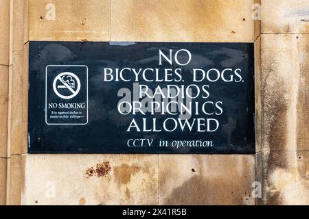 Schild, das Fahrräder, Hunde, Radios und Picknicks verbietet, an der Wand des Kings College, Cambridge University, mit einem Rauchverbot und CCTV-Hinweis. UK Stockfoto