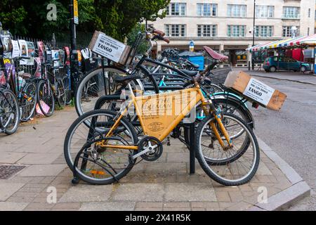 Fahrradwerbung für den Bikeman, Fahrradreparatur parkte neben Fahrrädern, die einen Tangokurs an einem überfüllten Fahrradstand in Cambridge, England, Großbritannien, bewerben Stockfoto