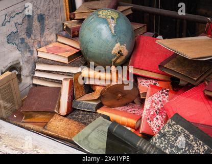 Schaufensterausstellung im Pariser Geschäft mit einem Stapel alter Bücher und einer großen Weltkugel Stockfoto