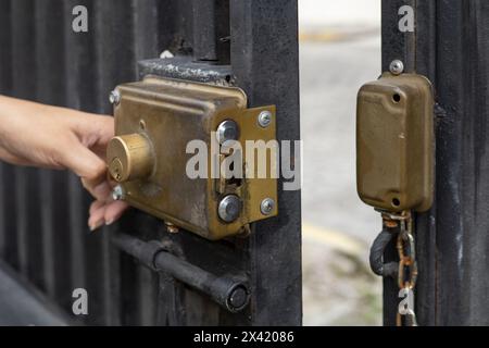 Die Hand einer Person, die das Schloss einer Metalltür öffnet, ein Sicherheitsobjekt, eine Tapete Stockfoto