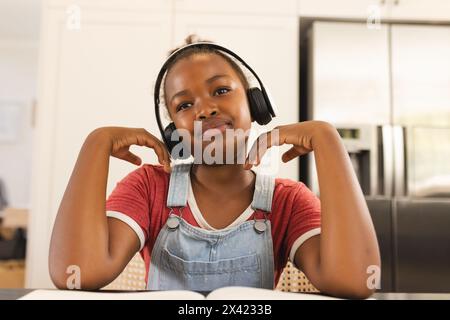 Afroamerikanisches Mädchen, das Kopfhörer trägt und zu Hause Musik genießt Stockfoto