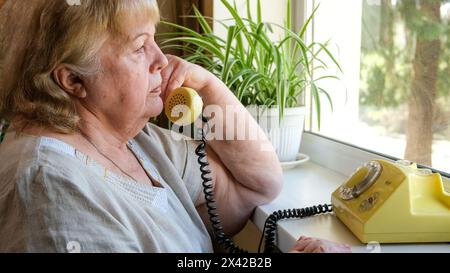Die alte Frau erhält einen Anruf. Großmutter spricht auf einem alten Disc-Handy Stockfoto