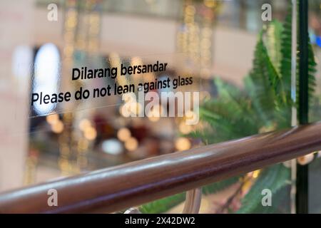 Aufkleber "bitte nicht gegen Glas lehnen" auf dem Glasgeländer. Stockfoto