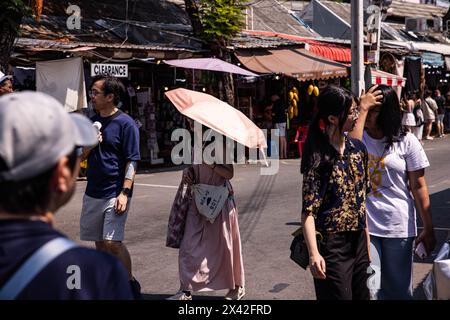 Bangkok, Thailand. April 2024. Touristen blockieren die Sonne mit Sonnenschirmen auf dem Chatuchak Markt während einer Zeit oder mit starken Hitzewarnungen der thailändischen Wetterbehörde in Bangkok, Thailand, am Sonntag, den 28. April 2024. Die Wettermuster in El Nino bringen überdurchschnittlich heißere Temperaturen, die bis Juni erwartet werden. (Kreditbild: © Andre Malerba/ZUMA Press Wire) NUR REDAKTIONELLE VERWENDUNG! Nicht für kommerzielle ZWECKE! Stockfoto