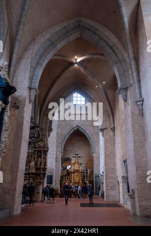 Trier, Rijnland-Palts, Deutschland, 23. März 2024, das Innere des Trierer Doms, ein Denkmal von religiöser Bedeutung, erschließt sich in einer Ausstellung von Hochmut und Pracht. Das Schiff erstreckt sich nach oben und zeigt die romanische Architektur der Kathedrale mit Elementen gotischen Designs. Die Besucher sind durchgehend gesprenkelt und bieten ein Gefühl von Skala und Ehrfurcht, während sie den komplizierten Altaraufsatz und das Spiel des Lichts durch die Fenster betrachten. Feierliches Inneres des Trierer Doms mit Besuchern. Hochwertige Fotos Stockfoto