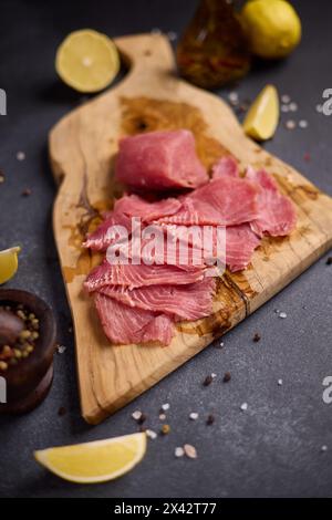 Frau Schnitt Thunfischsteak in Scheiben auf einem hölzernen Schneidebrett in der Hausküche, die Thunfisch-Carpaccio kocht Stockfoto