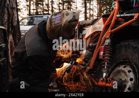 REPUBLIK KARELIEN, RUSSLAND - CA. JUNI 2022: Offroad-Turnier Ladoga Trophy 2022 rund um den Ladoga-See. Der Mechaniker repariert ein Motorrad nach dem Rennen mit einem Schleifer Stockfoto