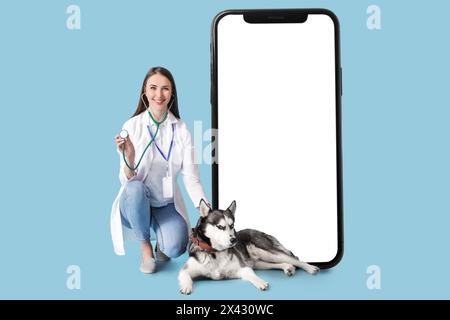 Tierärztin mit Husky Hund und großem Smartphone auf hellblauem Hintergrund Stockfoto