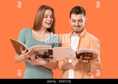 Junges Paar mit Zeitschriften auf orangem Hintergrund Stockfoto