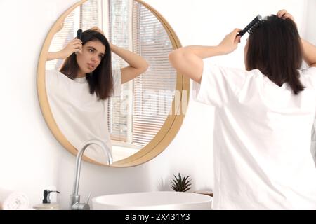 Junge Frau kämmt Haare im hellen Badezimmer Stockfoto