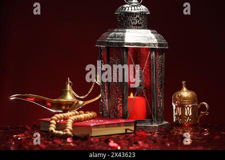 Arabische Laterne, Koran, misbaha und Aladdin magische Lampe auf glänzend rotem Tisch Stockfoto