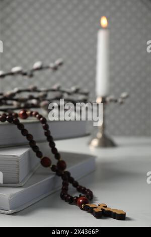 Rosenkranzperlen, Bücher und Weidenzweige auf weißem Tisch, Nahaufnahme Stockfoto