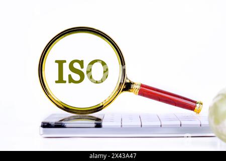 ISO. Internationale Organisation für Normung. Eine Word ISO-Inschrift wurde mit einer Lupe auf dem Rechner gefunden. Konzeptfoto Stockfoto