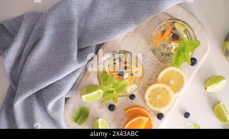 Sommerliche gesunde Cocktails aus Zitruswasser, Limonaden oder Mojitos, mit Limone Zitronenorange Blaubeeren und Minze, Diät Entgiftungsgetränke, in Gläsern Stockfoto