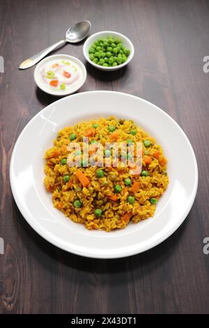 Karotten und Erbsen Pilaf oder Gajar Matar Pulao. Es ist ein eintöniges Reisgericht mit Basmati-Reis und Gemüse, gewürzt mit Gewürzen, serviert mit Joghurt Stockfoto