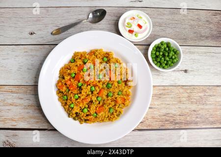 Karotten und Erbsen Pilaf oder Gajar Matar Pulao. Es ist ein eintöniges Reisgericht mit Basmati-Reis und Gemüse, gewürzt mit Gewürzen, serviert mit Joghurt Stockfoto