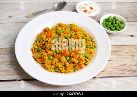Karotten und Erbsen Pilaf oder Gajar Matar Pulao. Es ist ein eintöniges Reisgericht mit Basmati-Reis und Gemüse, gewürzt mit Gewürzen, serviert mit Joghurt Stockfoto