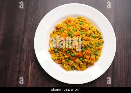 Karotten und Erbsen Pilaf oder Gajar Matar Pulao. Es ist ein eintöniges Reisgericht mit Basmati-Reis und Gemüse, gewürzt mit Gewürzen, serviert mit Joghurt Stockfoto