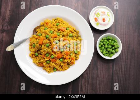 Karotten und Erbsen Pilaf oder Gajar Matar Pulao. Es ist ein eintöniges Reisgericht mit Basmati-Reis und Gemüse, gewürzt mit Gewürzen, serviert mit Joghurt Stockfoto