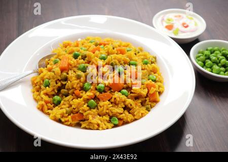 Karotten und Erbsen Pilaf oder Gajar Matar Pulao. Es ist ein eintöniges Reisgericht mit Basmati-Reis und Gemüse, gewürzt mit Gewürzen, serviert mit Joghurt Stockfoto