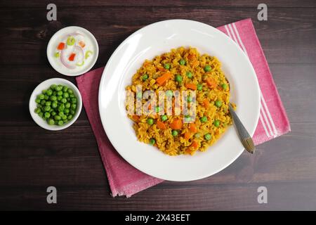 Karotten und Erbsen Pilaf oder Gajar Matar Pulao. Es ist ein eintöniges Reisgericht mit Basmati-Reis und Gemüse, gewürzt mit Gewürzen, serviert mit Joghurt Stockfoto