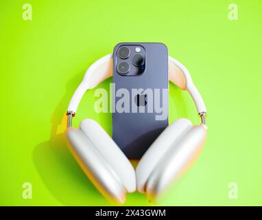 Paris, Frankreich, 29. September 2022: Die AirPods Max Kopfhörer von Apple bilden ein iPhone auf einem lebhaften grünen Hintergrund Stockfoto