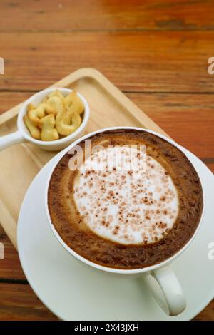 Tasse Cappuccino, serviert mit Keksen auf Holztisch Stockfoto
