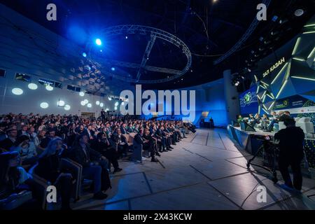 Moskau - 10. April 2024: Engagiertes Publikum, das bei einer Geschäftskonferenz in einem modernen Auditorium mit Rednern auf der Bühne und dynamischer Beleuchtung aufmerksam zuhörte. Stockfoto