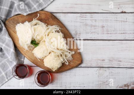 Östliche Süßigkeiten. Leckerer iranischer Paschmak und Tee auf weißem Holztisch, Blick von oben. Leerzeichen für Text Stockfoto