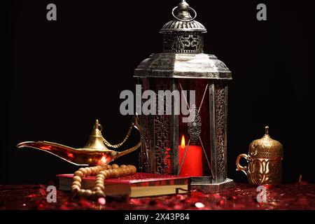 Arabische Laterne, Koran, misbaha und Aladdin magische Lampe auf glänzend rotem Tisch Stockfoto