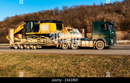 Transport- oder Abschleppwagen mit Baumaschinen-Bagger, Baggerlader, entlang der Autobahn Stockfoto